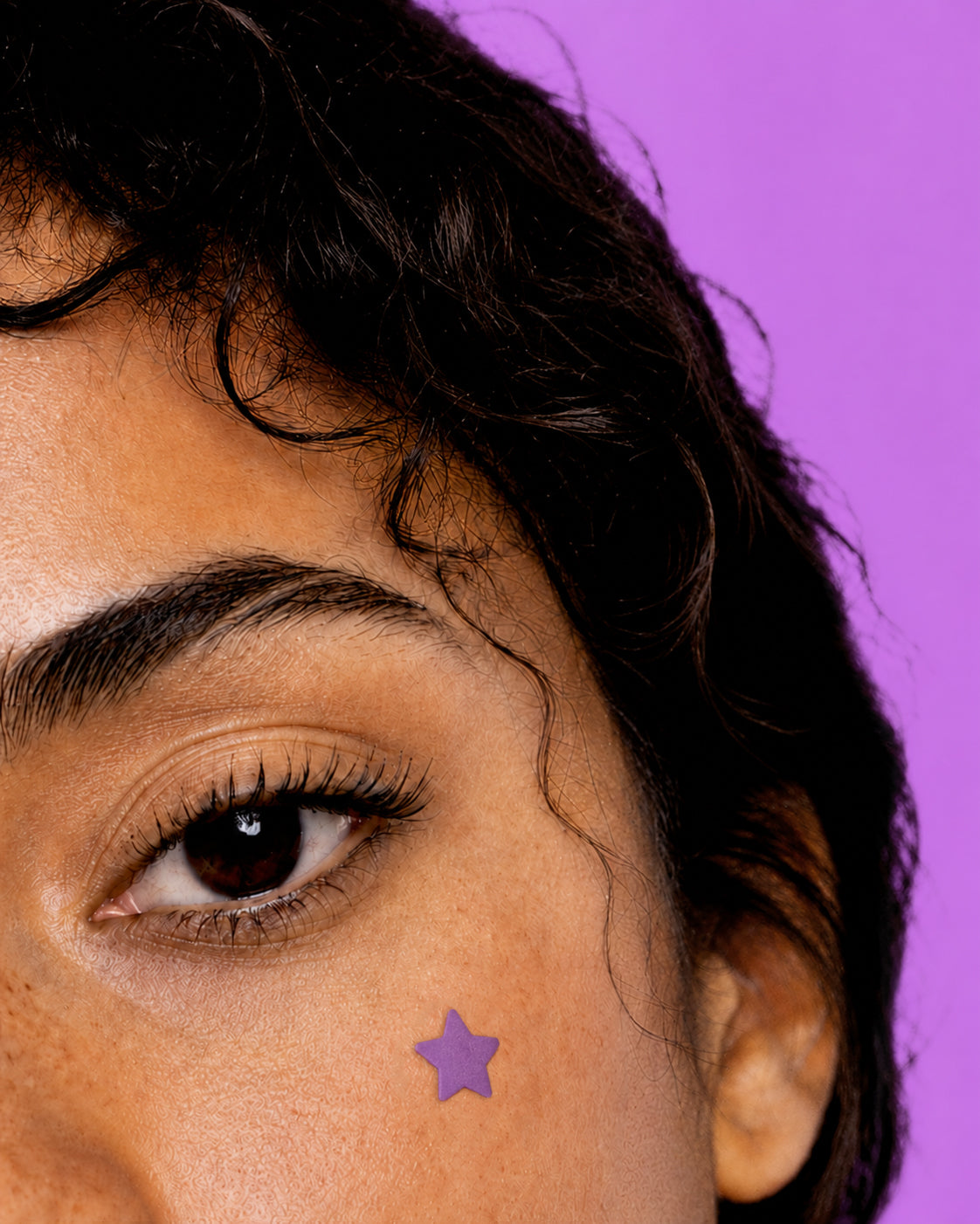 Persona mostrando un parche hidrocoloide para granos Stiq Patches Starwear con forma de estrella violeta (violet)