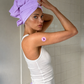 Una mujer con camiseta blanca en una zona de ducha utilizando un parche de vitaminas para relajarse de Stiq Patches Relax.